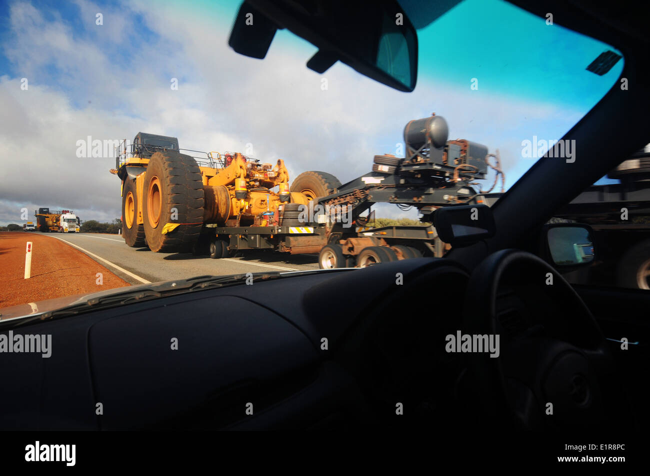 Auto tirata fuori autostrada per lasciare roadtrains portando massicce attrezzature minerarie passato, regione Pilbara, Australia occidentale Foto Stock