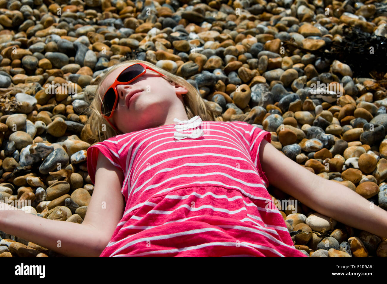 Giovane ragazza a prendere il sole sulla spiaggia di ghiaia Foto Stock