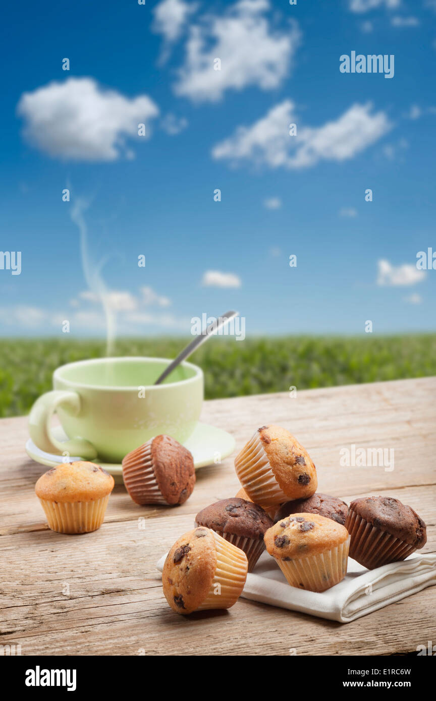 Una varietà di muffin piccolo con la tazza di tè sul tavolo di legno, con lo sfondo del paesaggio Foto Stock
