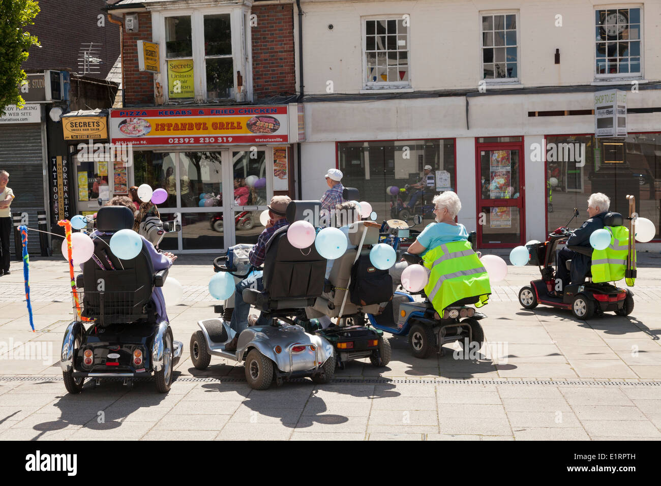Un gruppo di persone e non di una carità divertente correre in aiuto di Southampton Hospital sulla mobilità decorate scooter. Foto Stock