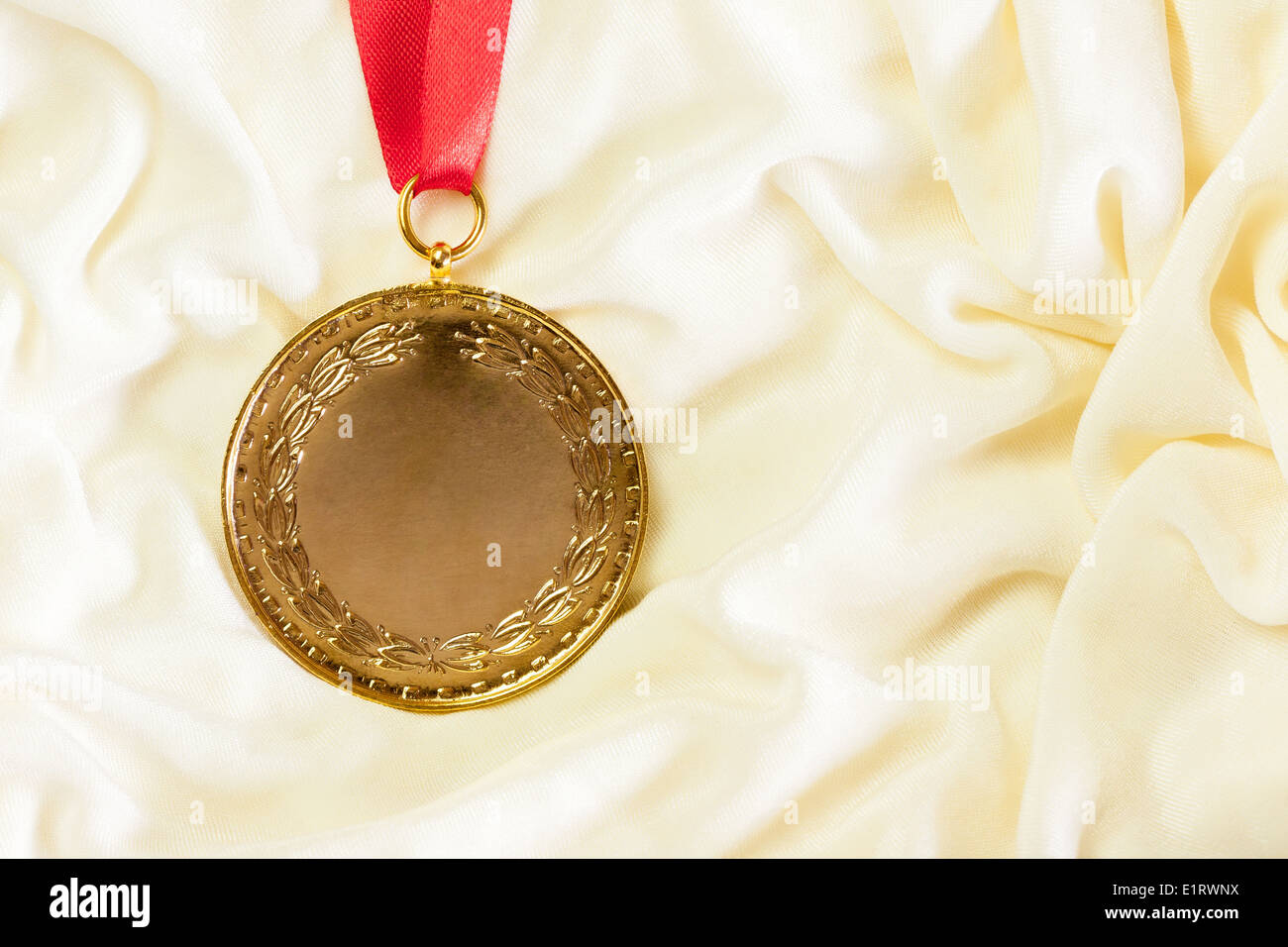 Un robusto medaglia d oro setup maestosamente contro una crema colorata panno di seta. Foto Stock