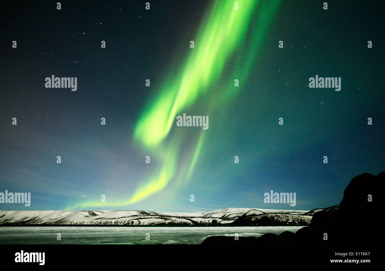 Le luci del nord brillano al di sopra di un lago ghiacciato al di fuori di Reykjavik in Islanda Foto Stock
