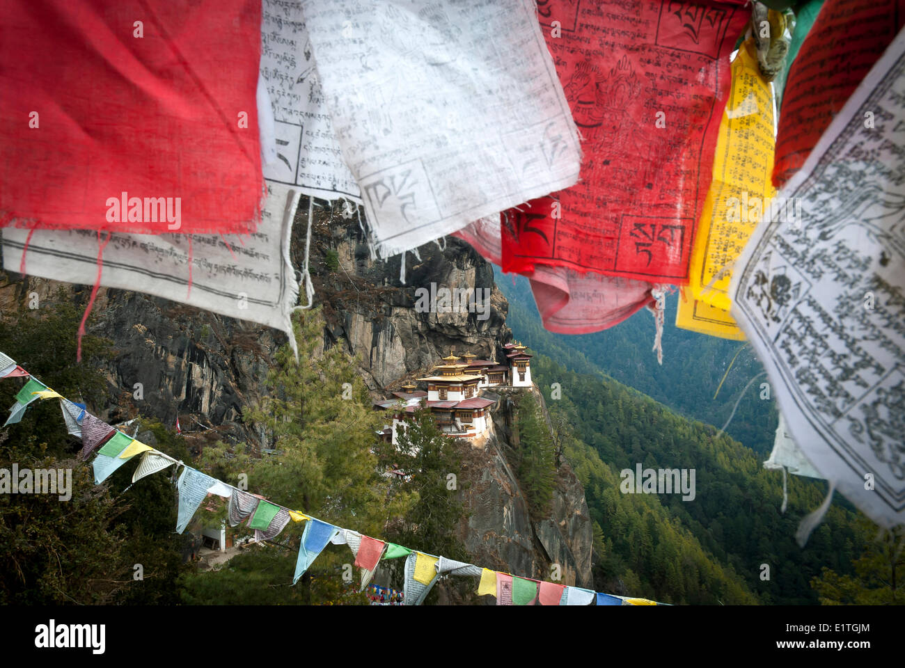 Taktsang Tigri (NEST) picchi di monastero fuori dietro alcune bandiere di preghiera al di sopra di Paro, Bhutan Foto Stock