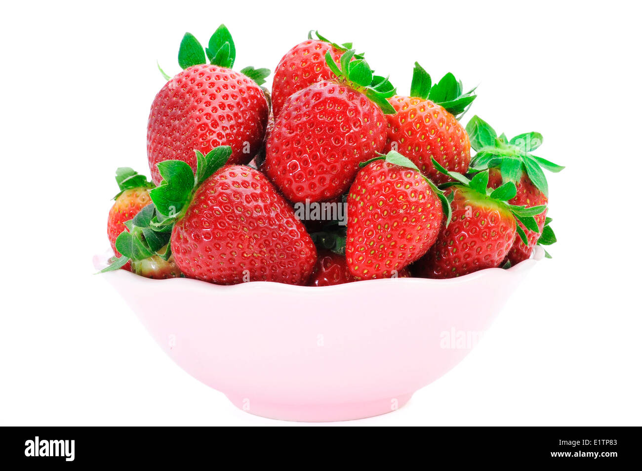 Un mucchio di appetitosi le fragole in un recipiente rosa su sfondo bianco Foto Stock