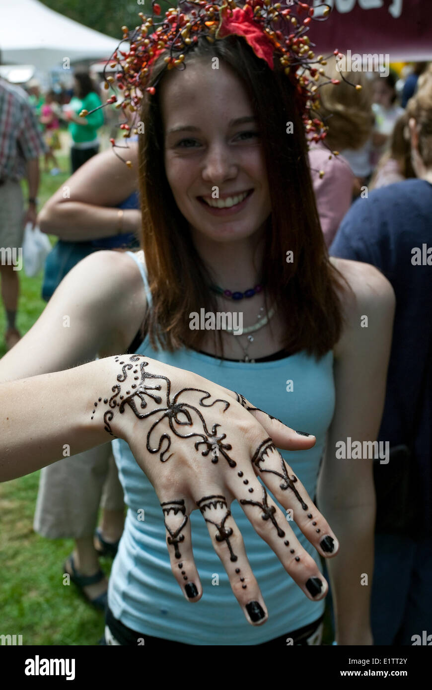 Una giovane donna visualizza la sua mano decorate e dipinte con henné, Comox, Isola di Vancouver, British Columbia, Canada Foto Stock