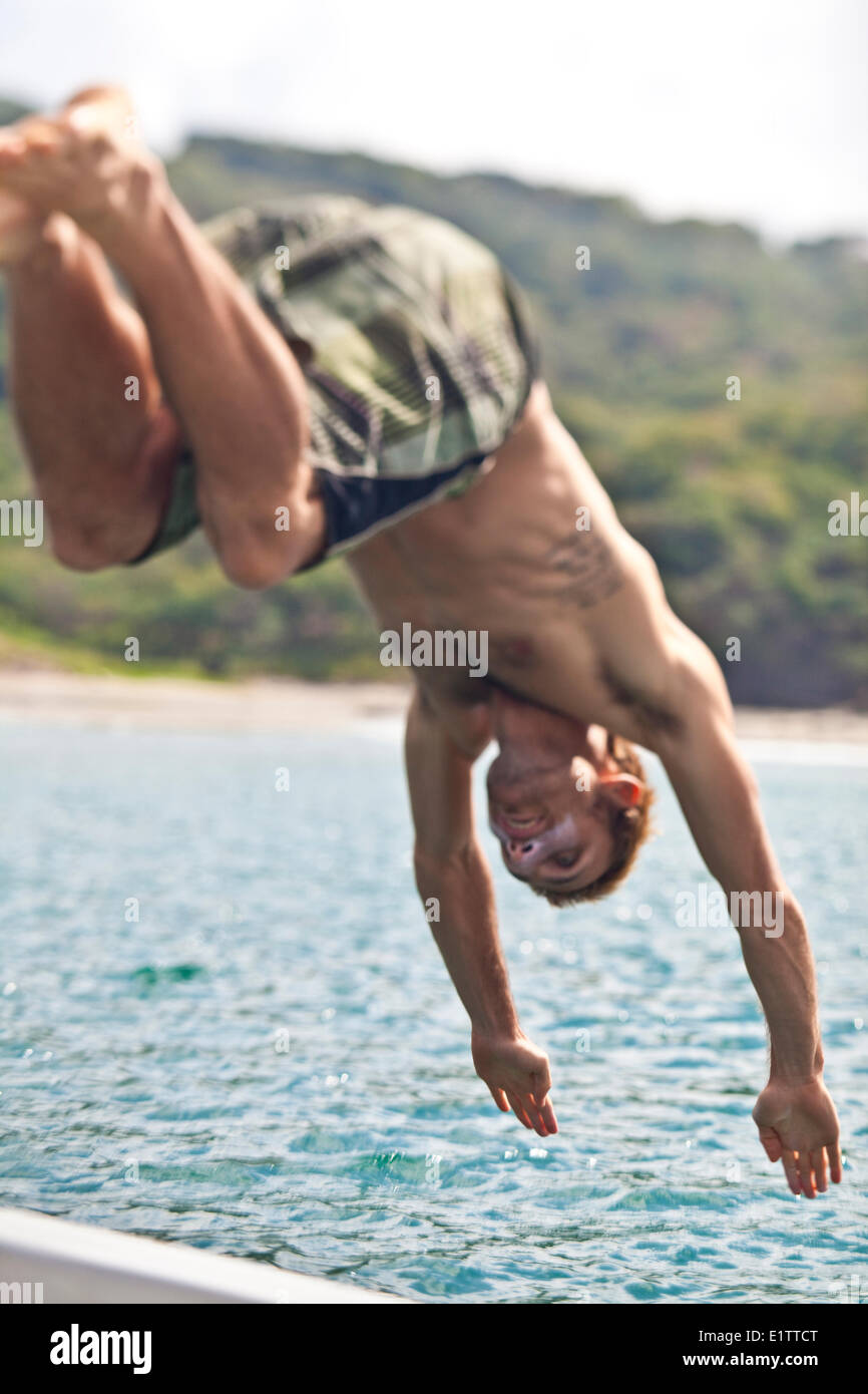 Un giovane uomo si tuffa fuori una barca in San Juan del Sur, Nicaragua Foto Stock