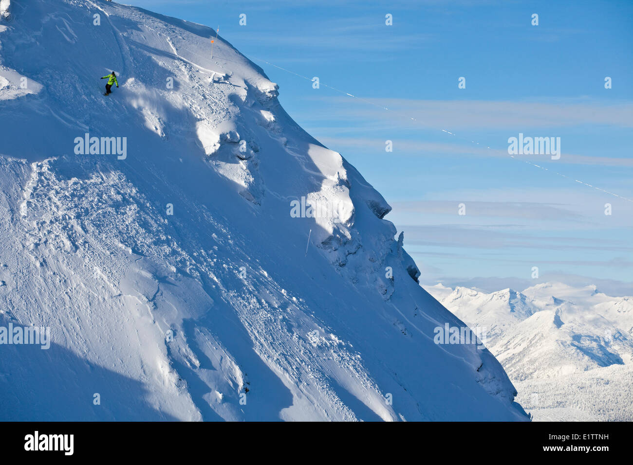 Un maschio snowboarder cavalca le piste di discesa alpina di Revelstoke Mountain Resort, BC Foto Stock