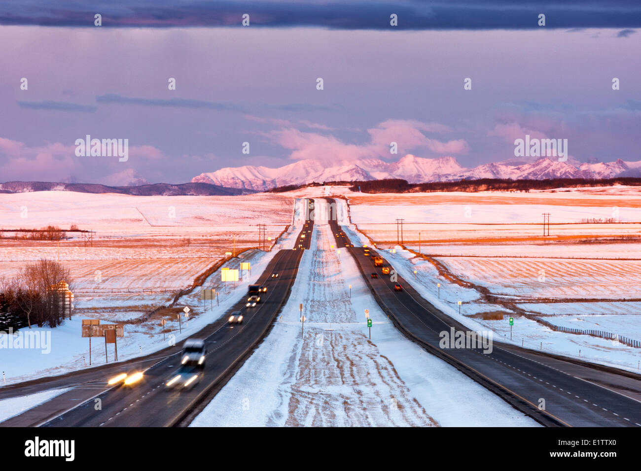 Vista di Trans-Canada Highway e Montagne Rocciose come sole sorge, saltando su strada di terra, Alberta, Canada Foto Stock