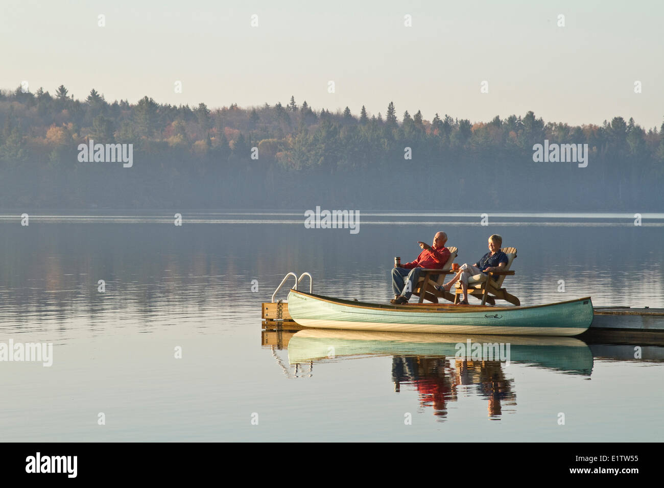 Coppia in pensione godere di sunrise cottage sul dock, lago di sorgente, Algonquin Park, Ontario, Canada. Foto Stock