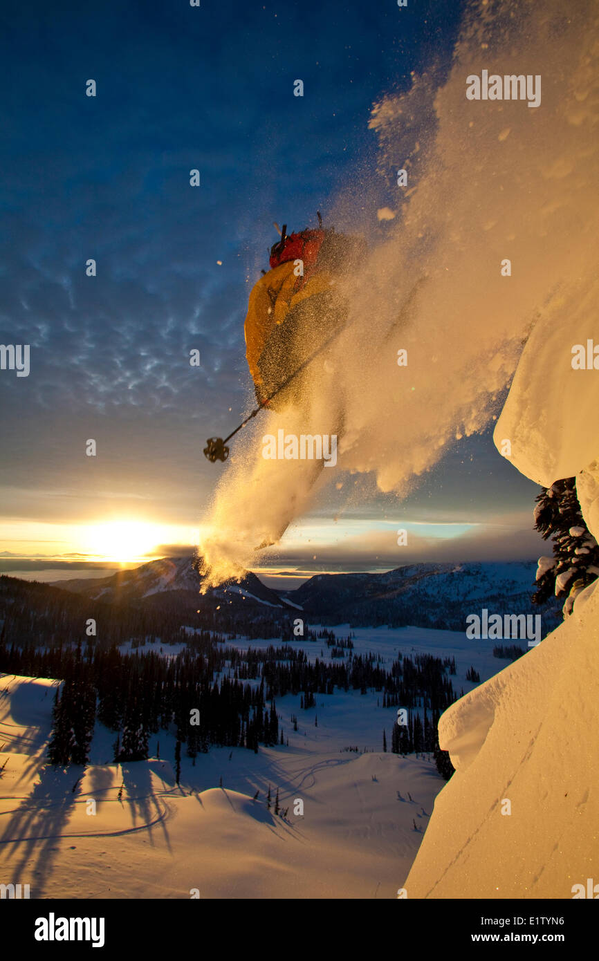Un maschio di backcountry rider scende una scogliera mentre fuori lo sci alpinismo a sunrise, Sol Mountain, Monashee Backcountry, Revelstoke, BC Foto Stock
