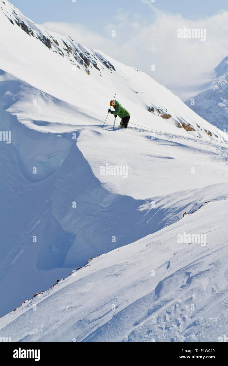 Un maschio di backcountry rider il taglio di un cornicione di fare alcune prove di pendenza prima di impegnare la linea di sci. Ghiacciaio Lodge, Golden, BC Foto Stock
