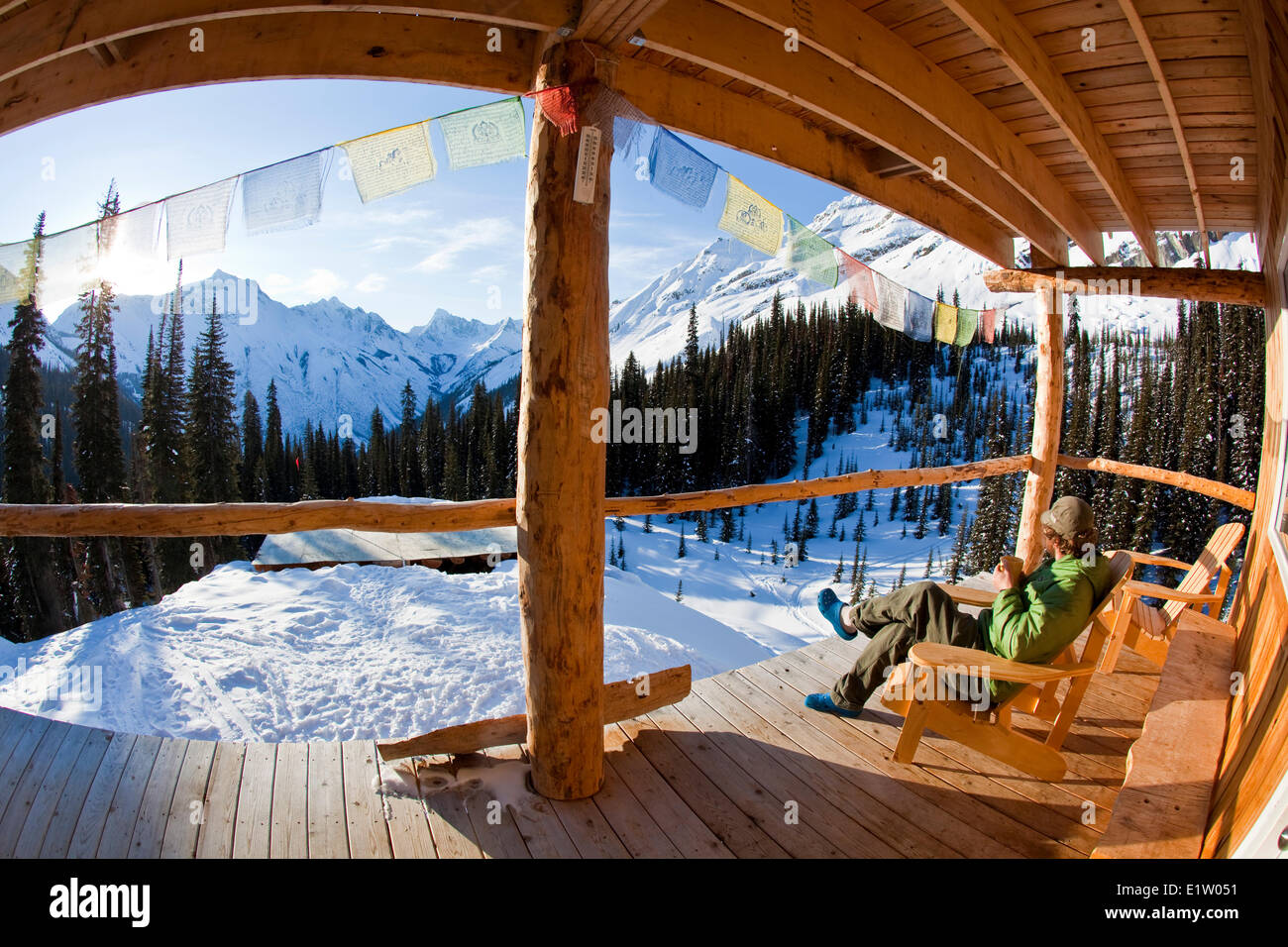 Un uomo godendo di mattina presto all'alba e un caffè in una backcountry Ski lodge. Ghiacciaio Lodge, Golden, BC Foto Stock