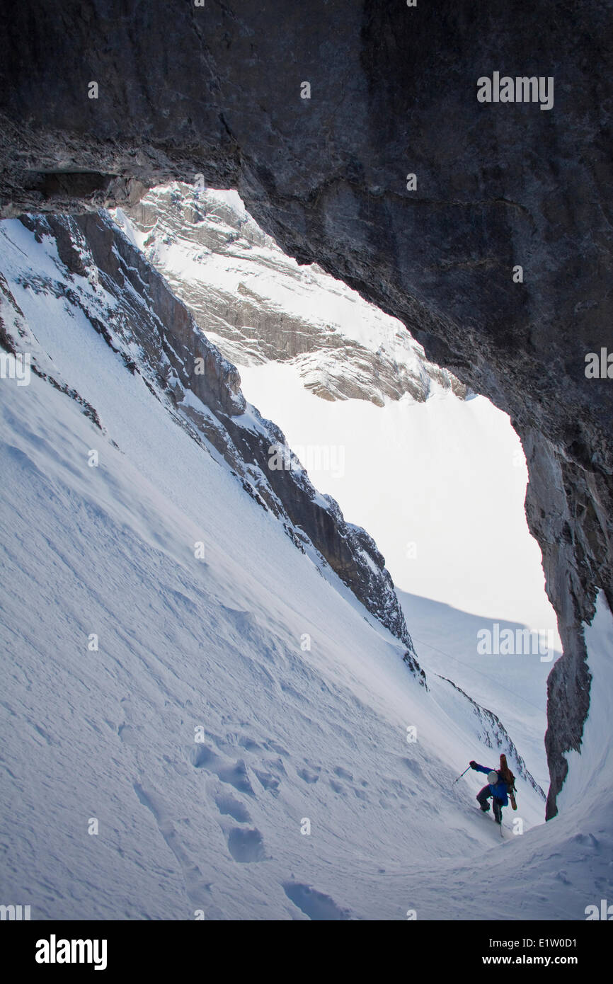 Un maschio di backcountry rider bootpacks su una ripida couloir con un unico arco calcareo in esso. Mt. Il francese Peter Lougheed provinciale Foto Stock