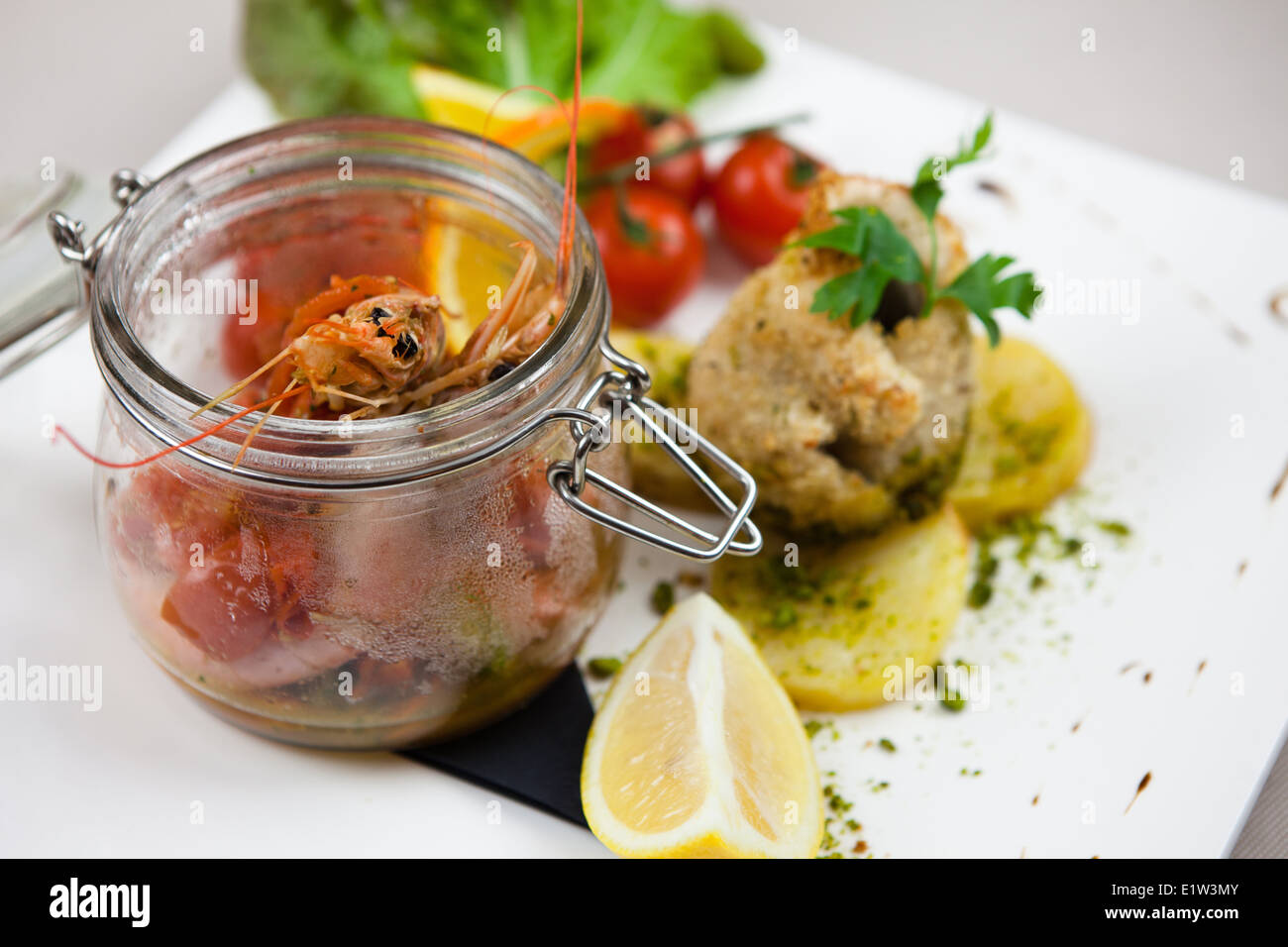 Zuppa di pesce con riso, gamberi e pesce, patate arrosto, pomodori e limone Foto Stock