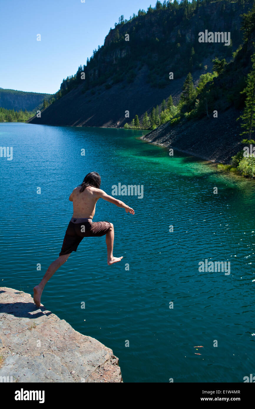 Un giovane uomo di cliff jumping vicino al Fernie, BC sulla torrida giornata estiva. Foto Stock