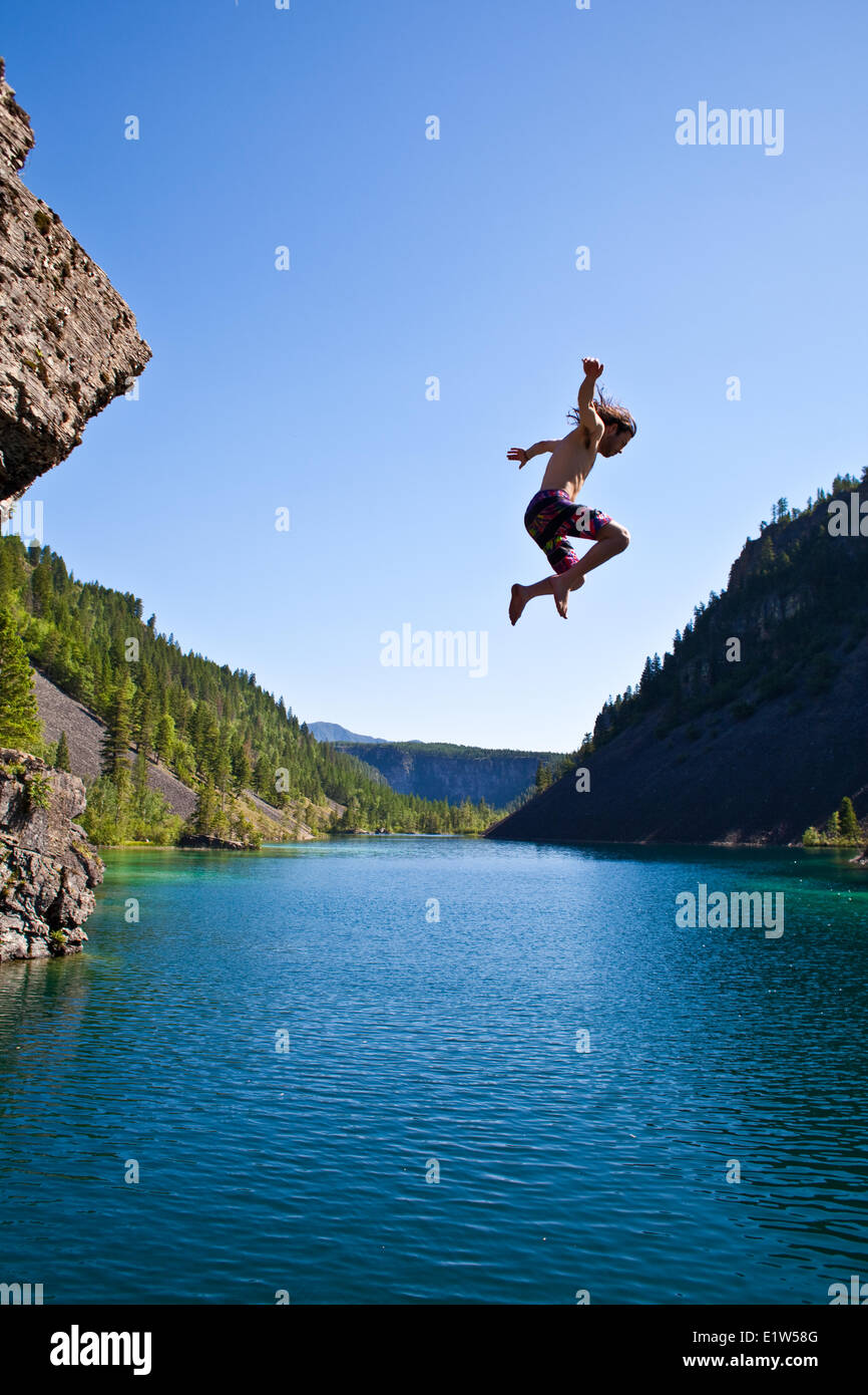 Un giovane uomo di cliff jumping vicino al Fernie, BC sulla torrida giornata estiva. Foto Stock
