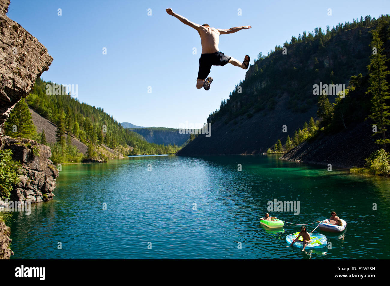 Un giovane uomo di cliff jumping vicino al Fernie, BC sulla torrida giornata estiva. Foto Stock