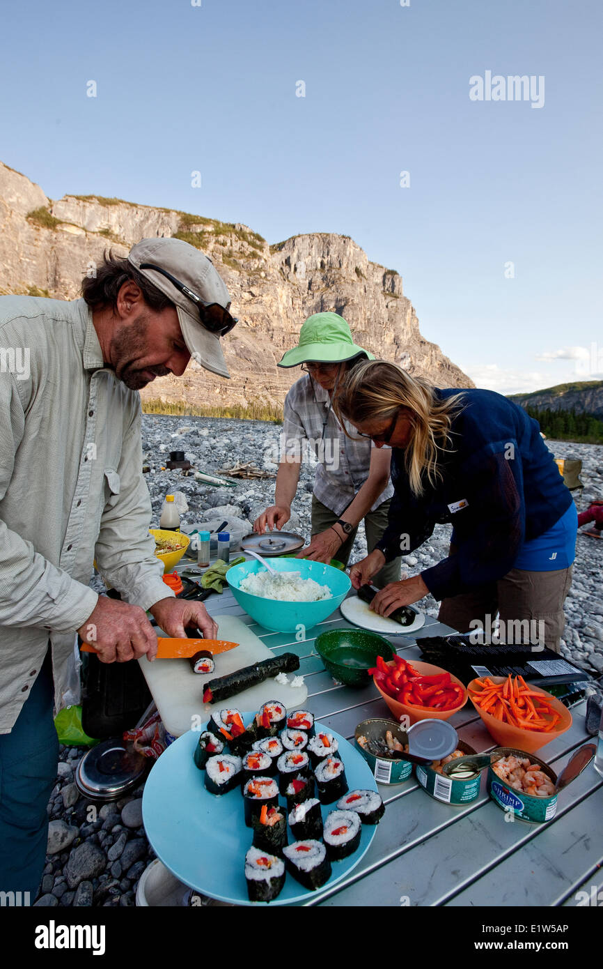 Tre adulti preparare sushi mentre si accampò sul fiume Nahanni, Parco Nazionale Nahanni preservare, NWT, Canada. Foto Stock
