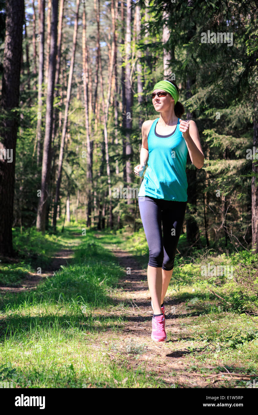 Donna jogging attraverso la foresta a primavera Foto Stock