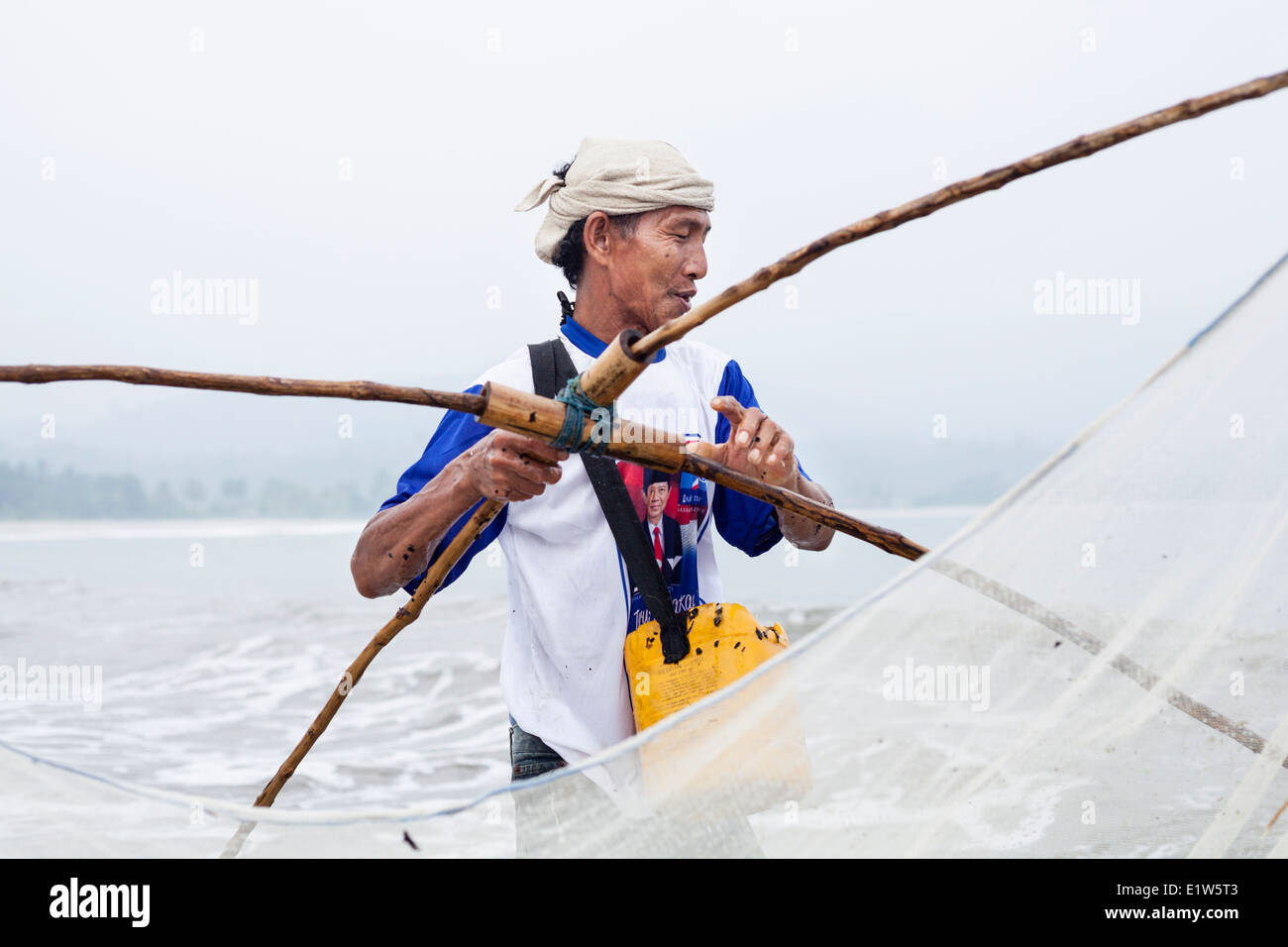 Un pescatore a Sumatra, Indonesia, utilizza un ben costruite net per la cattura di pesci da esca in shore break in una spiaggia a Pugung Tampak. Foto Stock