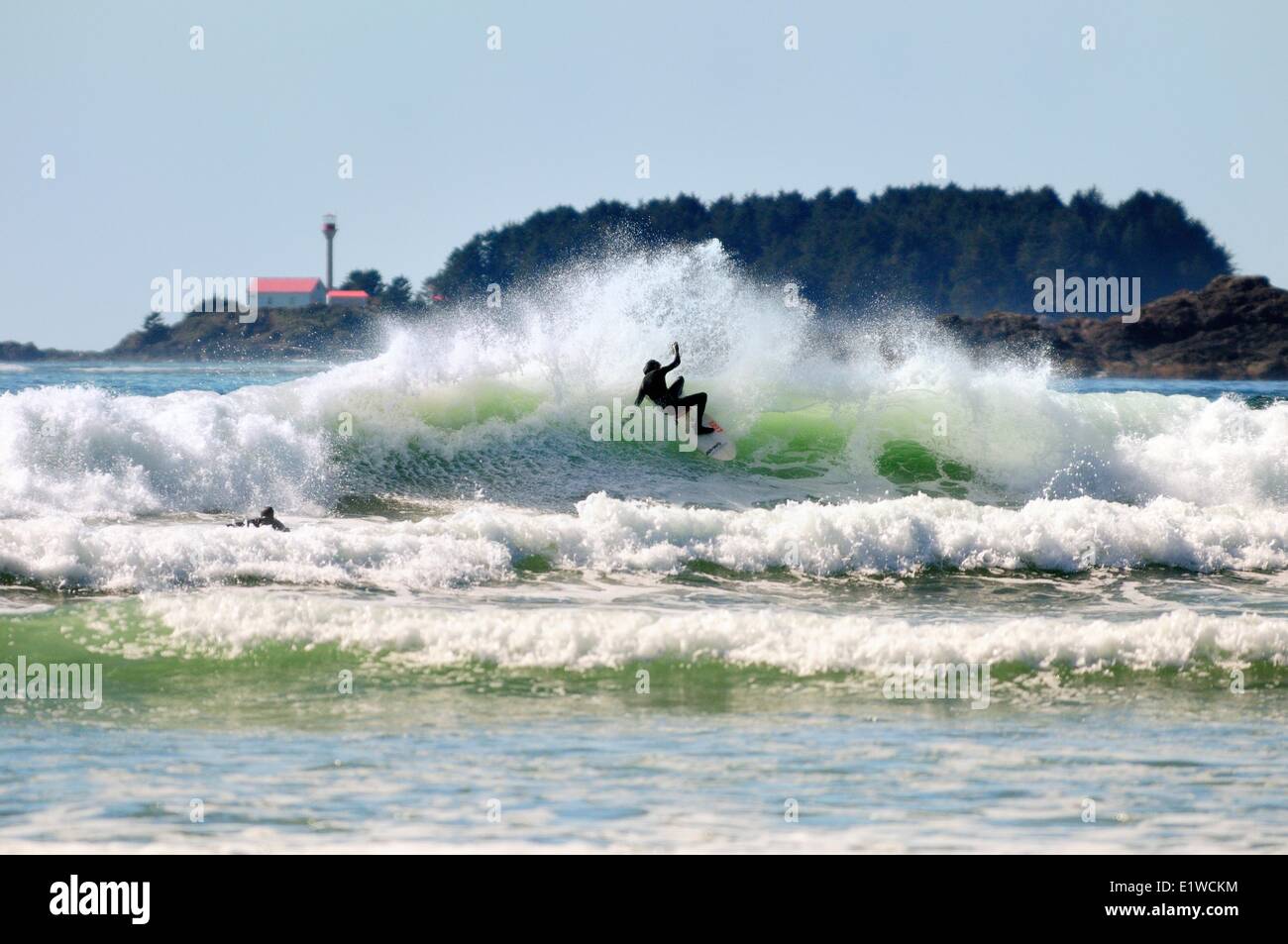 Un surfista fa un taglio mentre sulla parte superiore di una forma d'onda a Cox Bay a Tofino, BC. Foto Stock