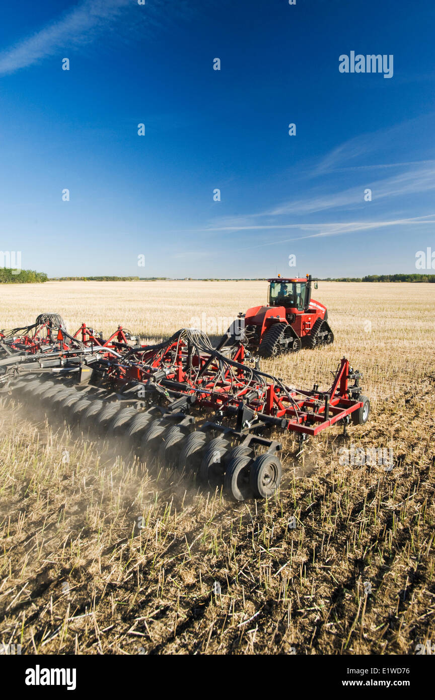 Trattore in movimento e aria e fino a una seminatrice piantagione di grano di inverno in uno zero fino a canola campo di stoppie, Lorette, Manitoba, Canada Foto Stock