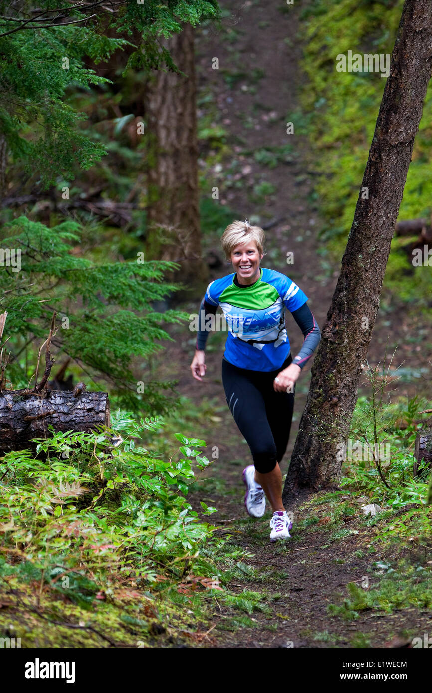 Una donna corre fino alla cima di una collina in i sentieri intorno al Lazo Marsh in Comox. Il Comox Comox Valley Vancouver Island British Columbia Foto Stock