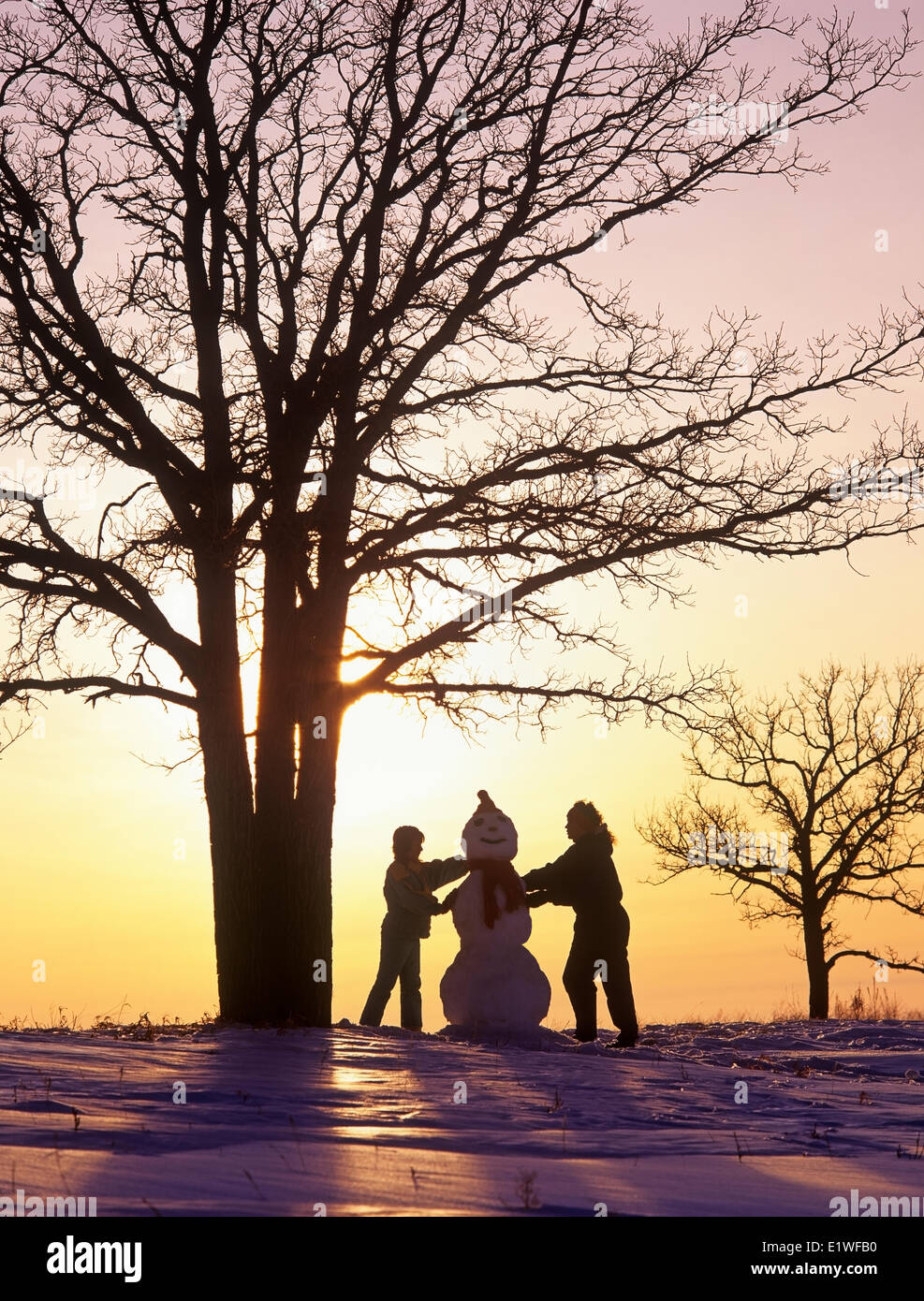 Madre e figlia fanno un pupazzo di neve, Uccelli Collina Parco Provinciale, Manitoba, Canada Foto Stock