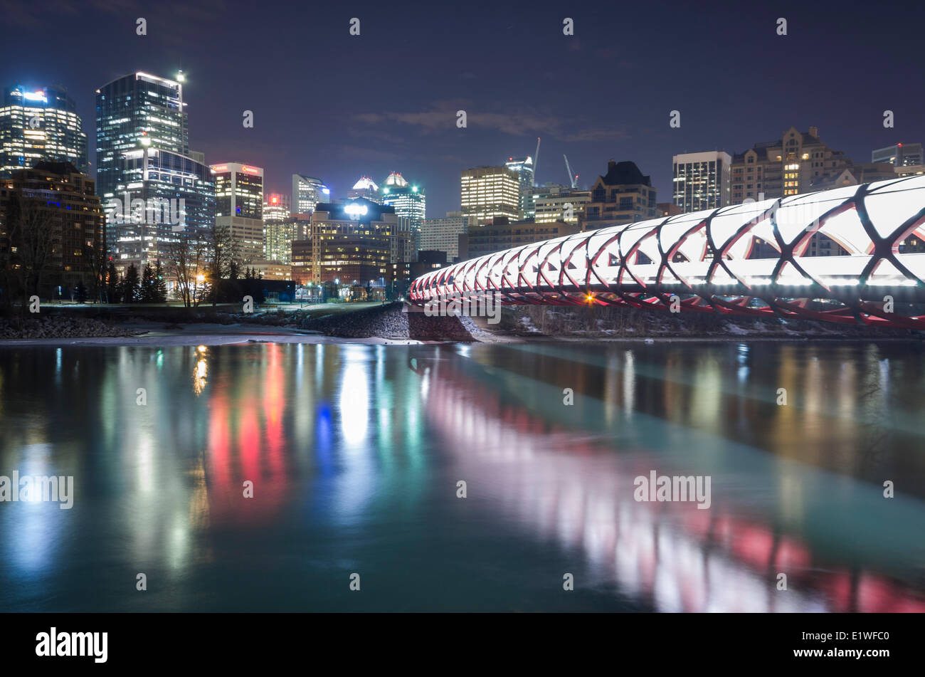 Pedonale ponte di pace e il centro cittadino di Calgary riflettente nel Fiume Bow di notte. Calgary, Alberta, Canada. Foto Stock