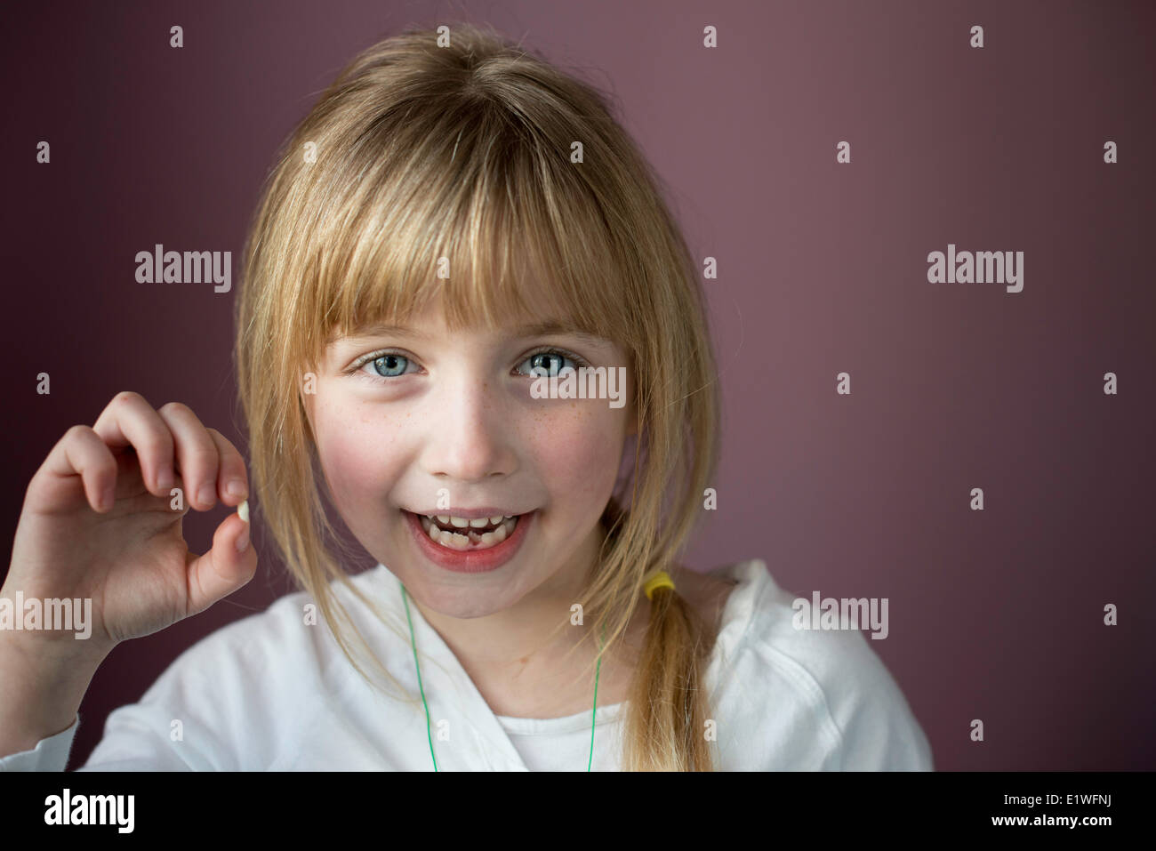 Ritratto di sorridente bambina che mostra il suo primo dente allentato Foto Stock