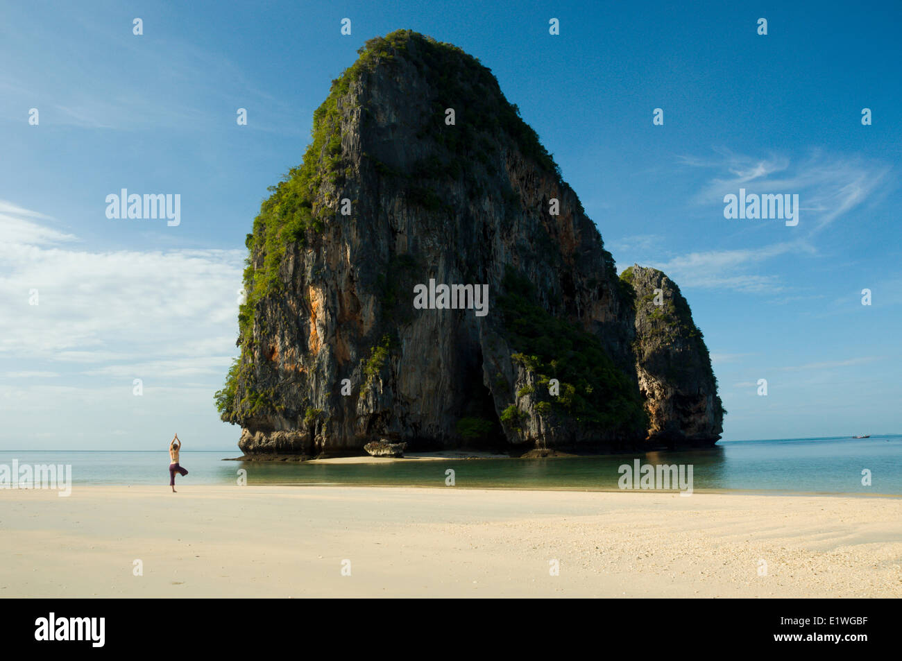 Una giovane donna fare yoga sulla spiaggia di fronte all'isola felice, Phra Nang Beach, Krabi, Thailandia Foto Stock