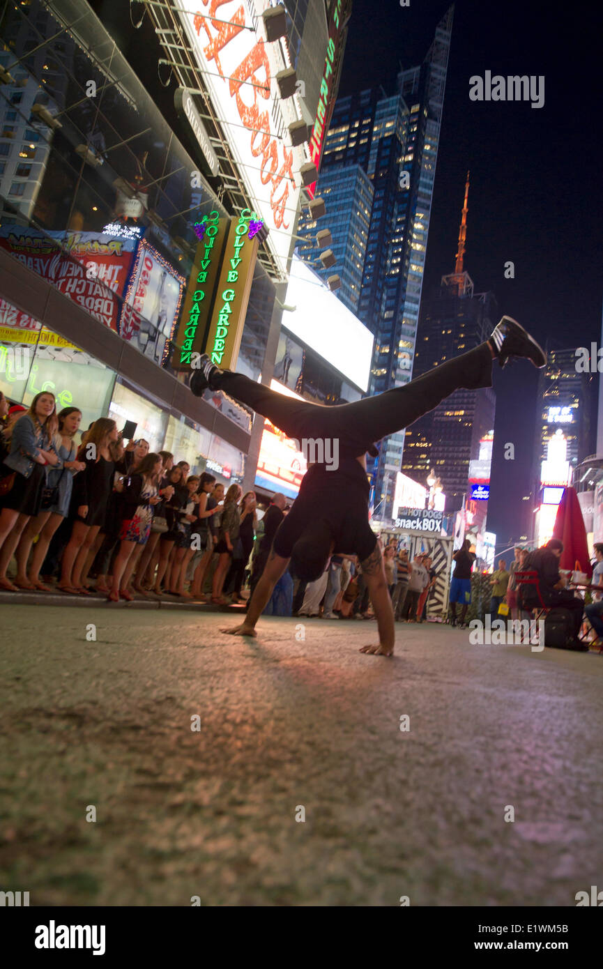 Street performer si erge sulle sue mani durante una performance atletica su Times Square a New York Foto Stock