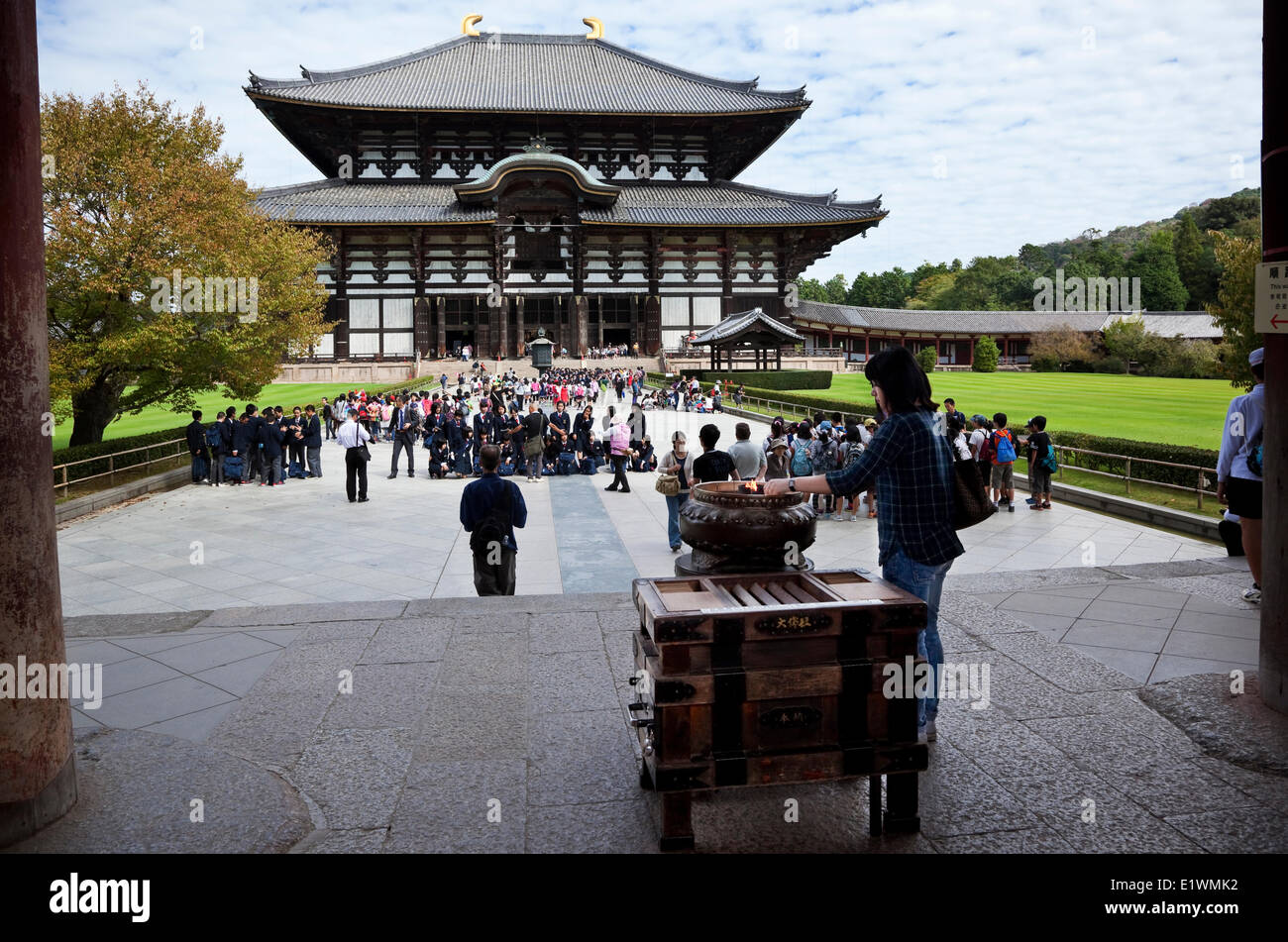 Un visitatore in piedi accanto a un koro (bruciatore di incenso) illuminazione e incenso stick a uno di Giappone più storicamente significativo te Foto Stock