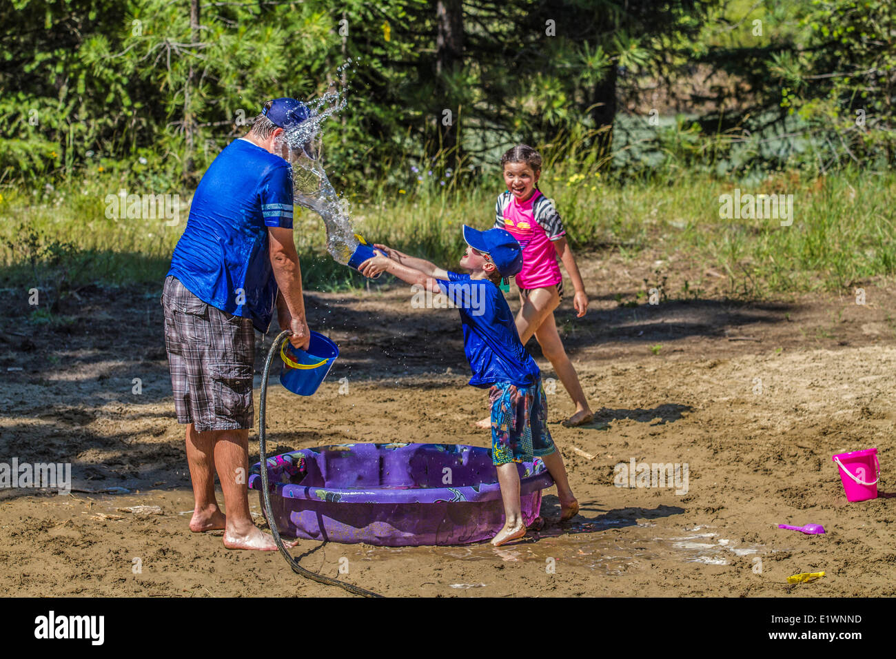 Per adulti e bambini in acqua playfull lotta , su una calda e soleggiata giornata estiva. Cranbrook, British Columbia, Canada. Foto Stock