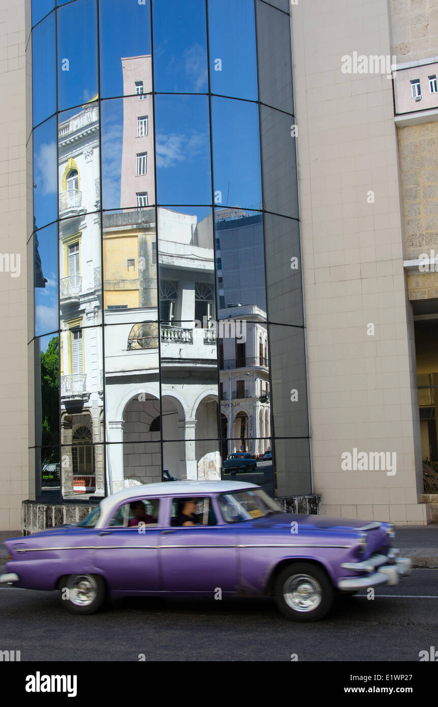 Vecchia auto americane riflettono in angolato edificio di vetro, Havana, Cuba Foto Stock