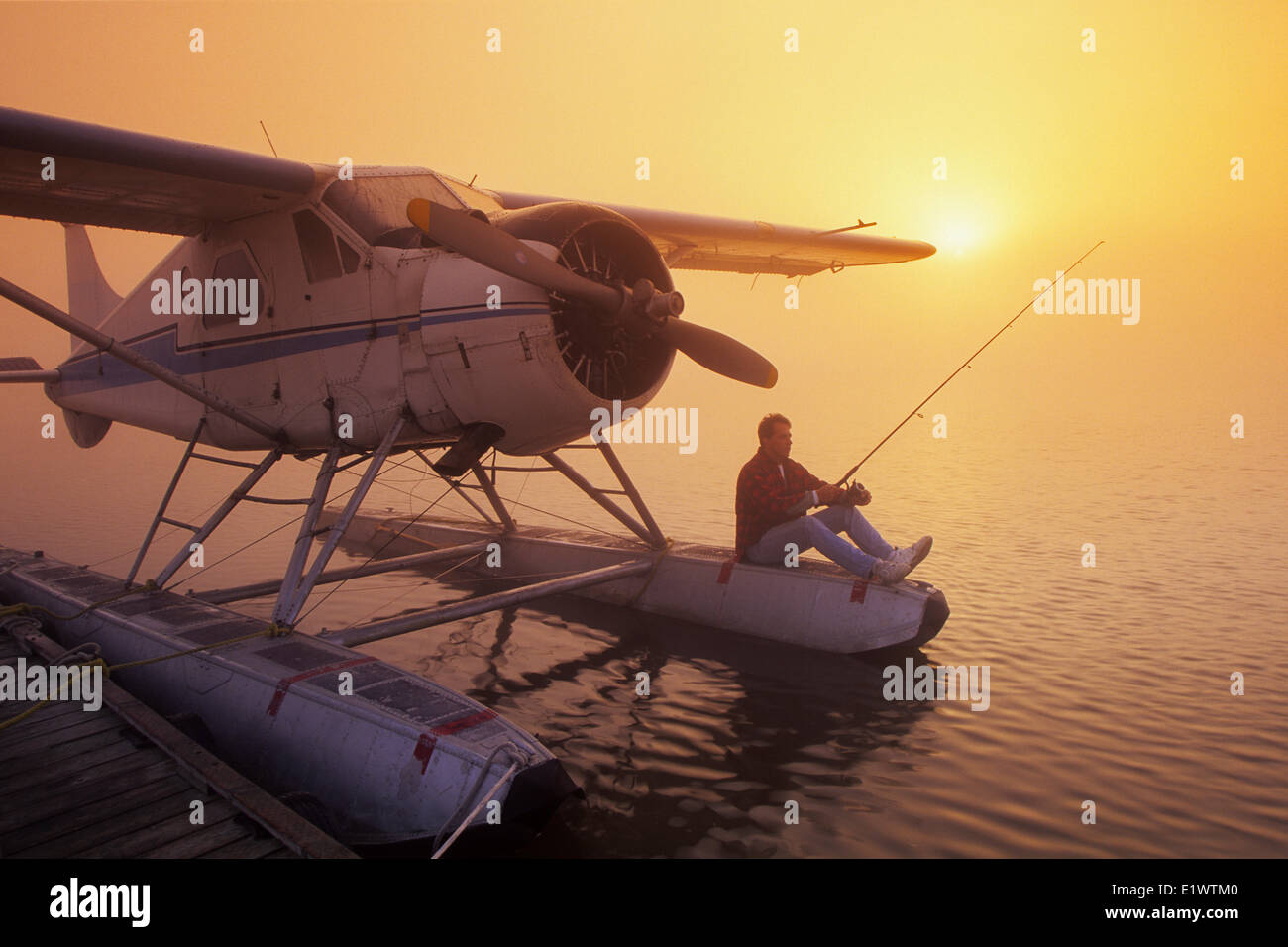 L'uomo la pesca dalla flottazione piano, lungo il Fiume Rosso, Manitoba, Canada Foto Stock
