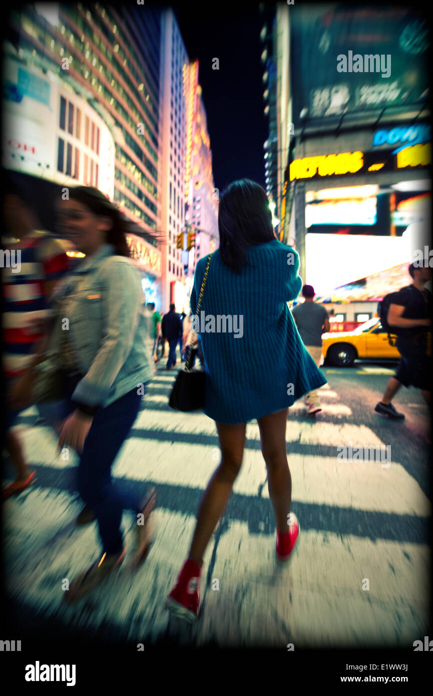 Giovane donna attraversando via a Times Square a New York Foto Stock