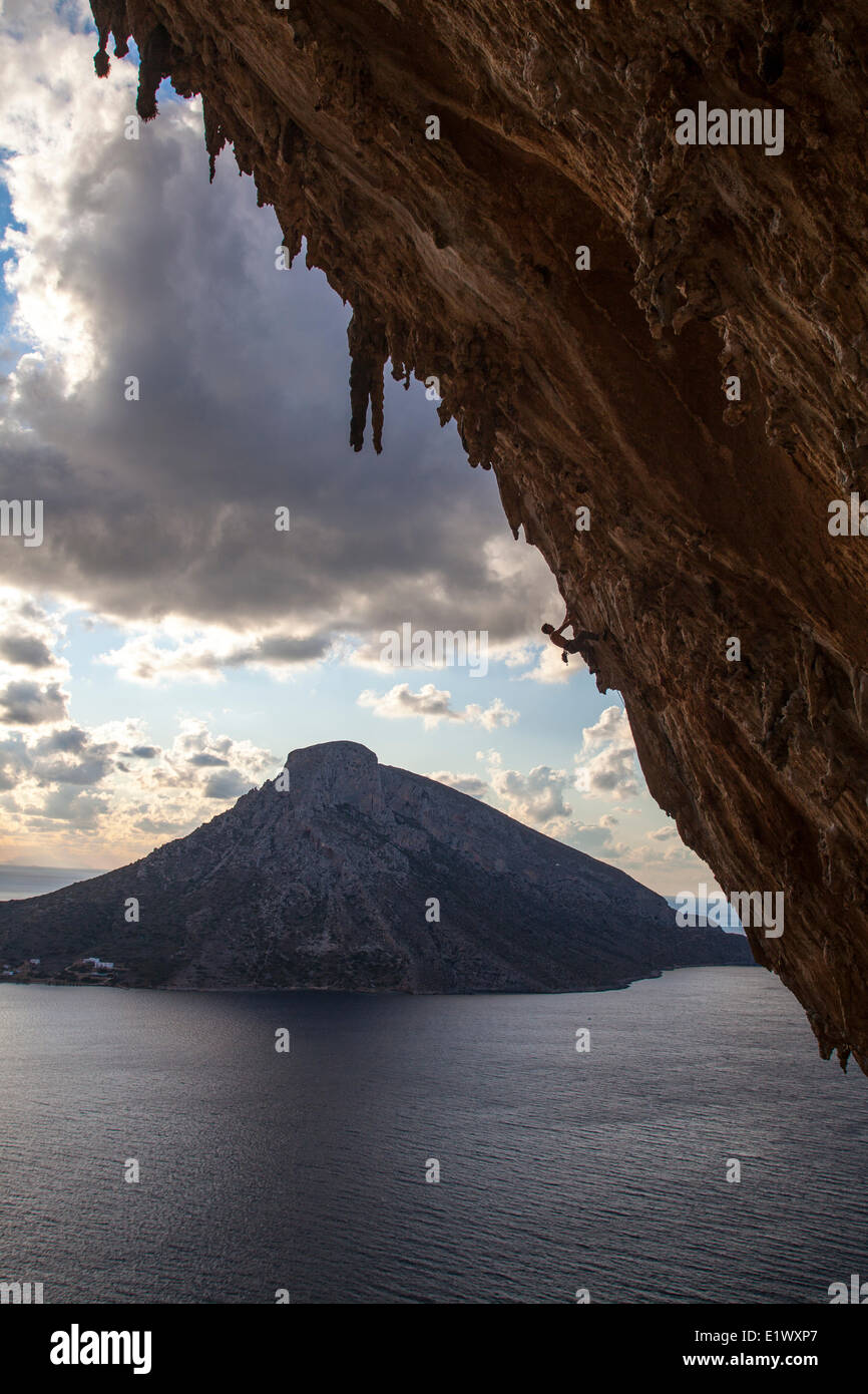Un maschio di scalatore ascende attraverso la selvaggia calcare formazioni rocciose nell'enorme grotta di Grand Grotta, Kalymnos, Grecia Foto Stock