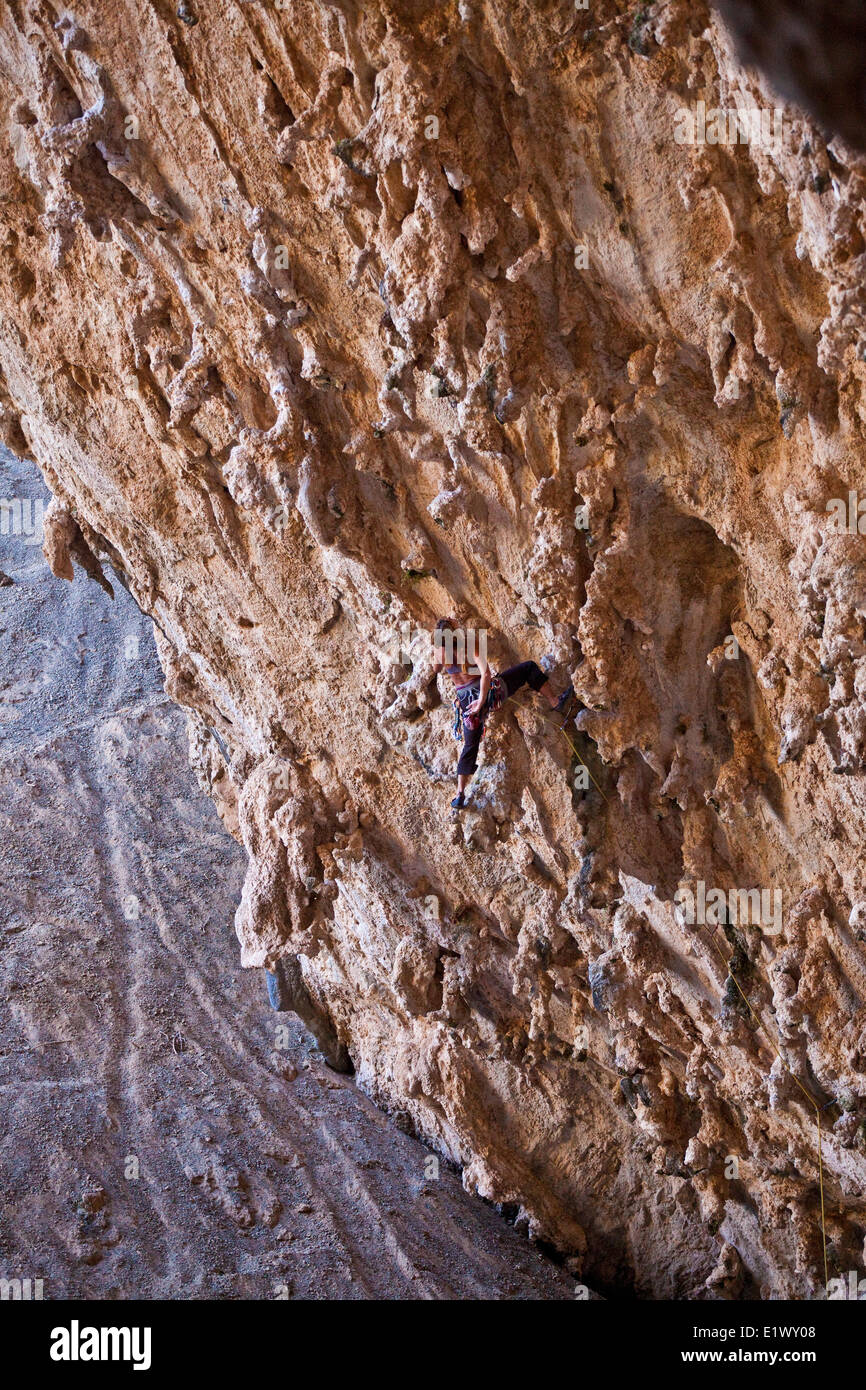 Un forte scalatore femmina ascende attraverso il calcare tufas di Morgan 7b+, Sitkati Grotta, Kalymnos, Grecia Foto Stock