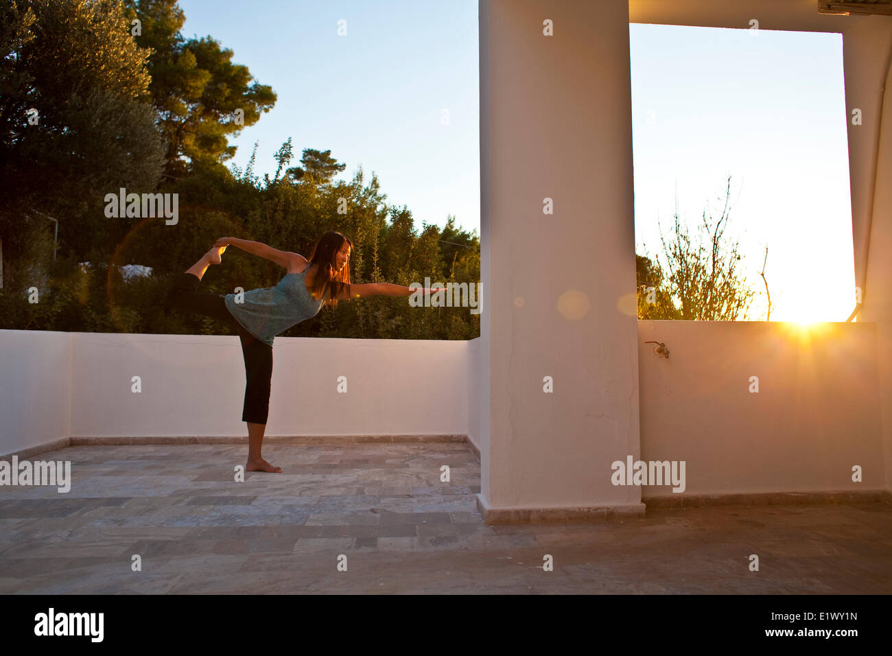 Una giovane donna non lo yoga al di fuori del suo studio mentre su un viaggio di arrampicata a Kalymnos, Grecia Foto Stock