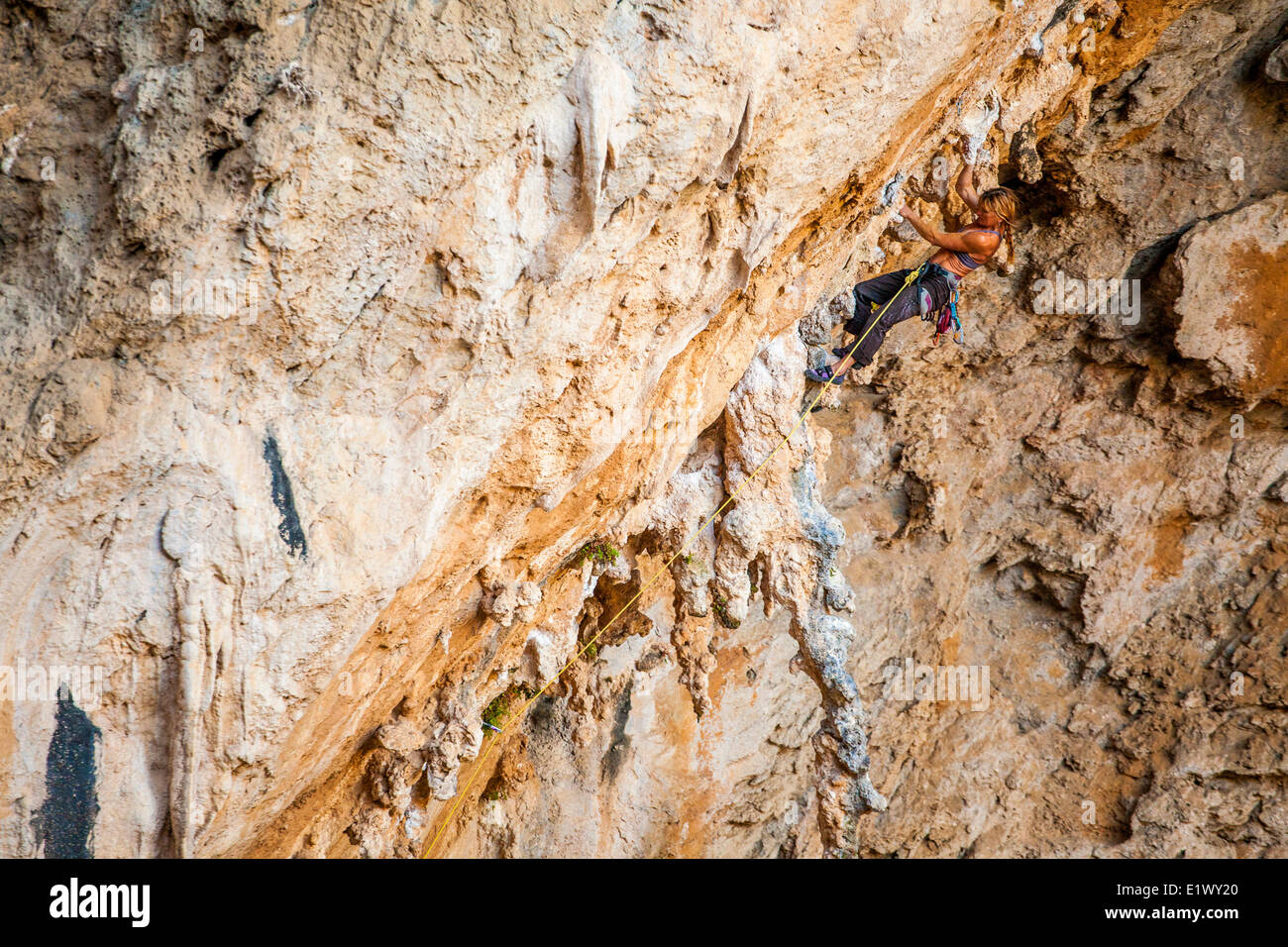 Un forte scalatore femmina ascende attraverso il calcare tufas di Morgan 7b+, Sitkati Grotta, Kalymnos, Grecia Foto Stock