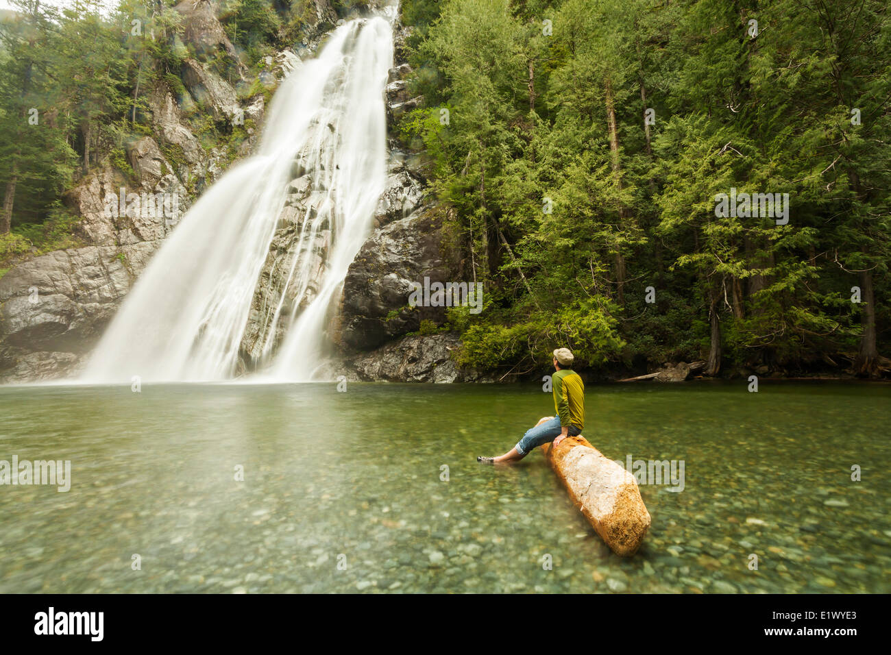 Un uomo maturo orologi una cascata durante i momenti di relax vicino a Clayoquot Sound. Tofino Vancouver Island British Columbia Canada Foto Stock