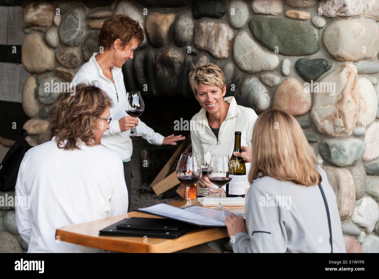 Quattro amici gustare un bicchiere di vino la conversazione in attesa per un tavolo a Sobo è un ristorante elegante in Tofino Tofino Vancouver Foto Stock