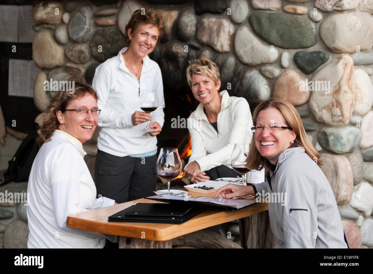 Quattro amici gustare un bicchiere di vino la conversazione in attesa per un tavolo a Sobo è un ristorante elegante in Tofino. Tofino Vancouver Foto Stock