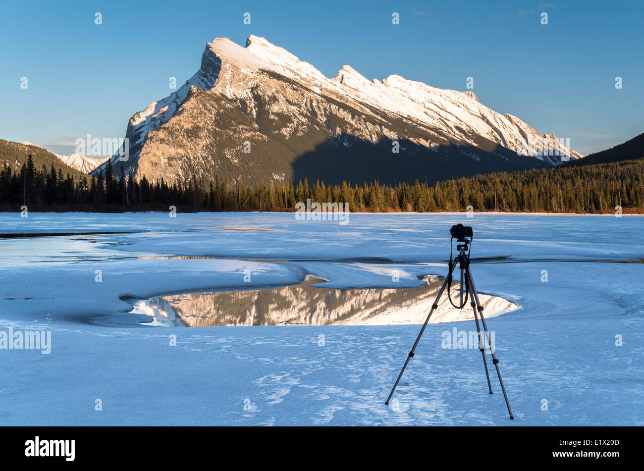 La fotocamera su un treppiede rivolta verso il Mount Rundle su congelati laghi Vermiglio al tramonto in inverno, il Parco Nazionale di Banff, Alberta, Canada Foto Stock