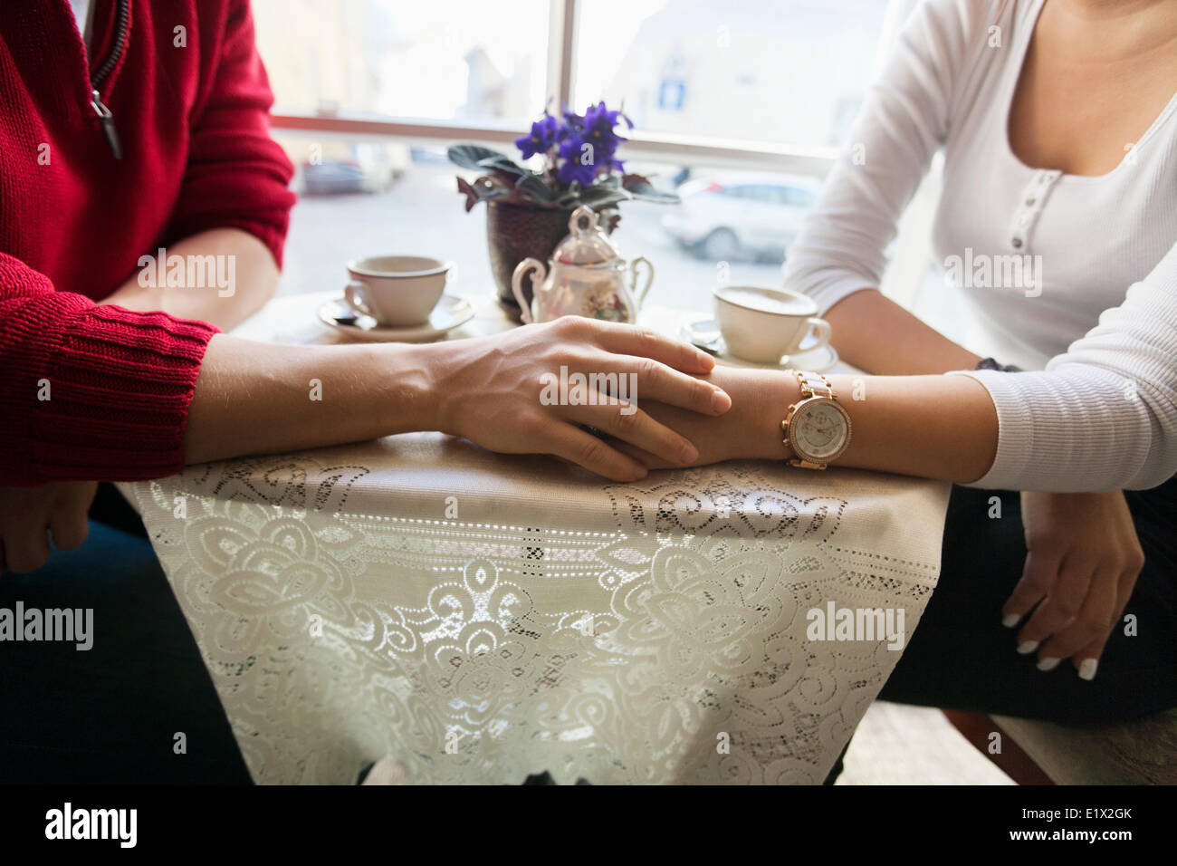 Sezione mediana del giovane holding hands in cafe Foto Stock