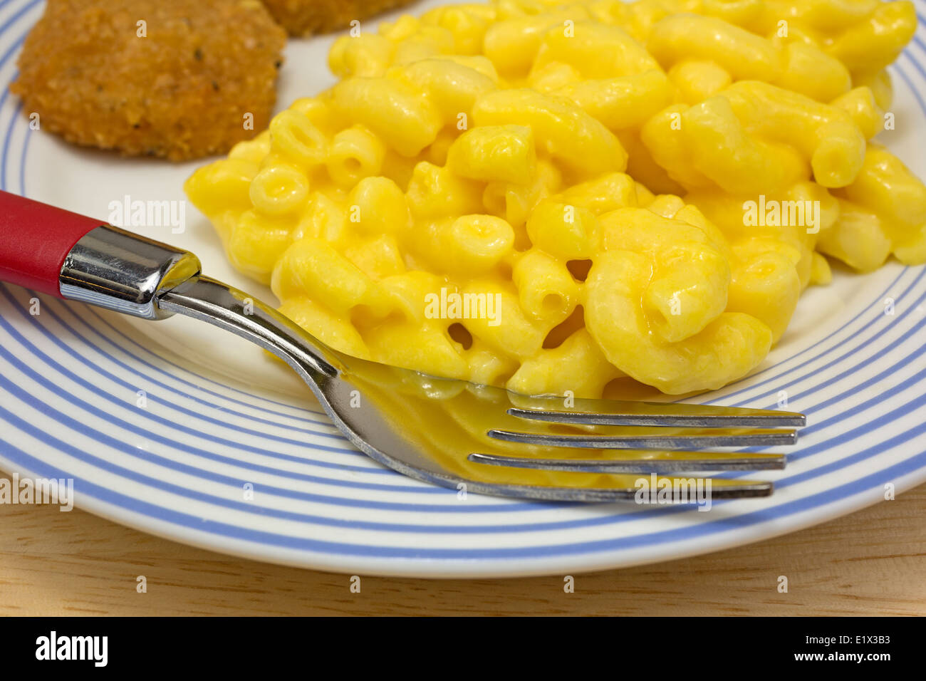 Chiudere la vista di un pasto di pepite di pollo con maccheroni e formaggio su una piastra con la forcella. Foto Stock