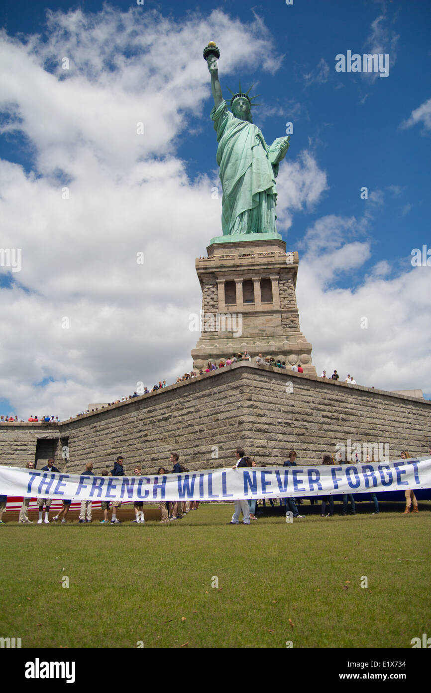 Un francese associazione no profit chiamato il francese non potrà mai dimenticare, sollevare un banner di fronte alla statua della libertà durante una cerimonia di commemorazione del settantesimo anniversario del D-Day su Liberty Island Giugno 6, 2014 nella città di New York, NY. Foto Stock