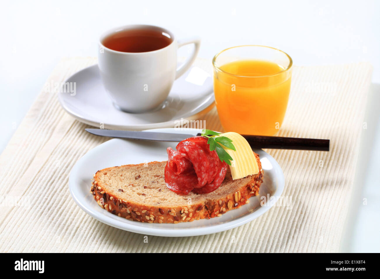 Ancora in vita di pane con salame, tazza di tè e caffè e succo d'arancia Foto Stock