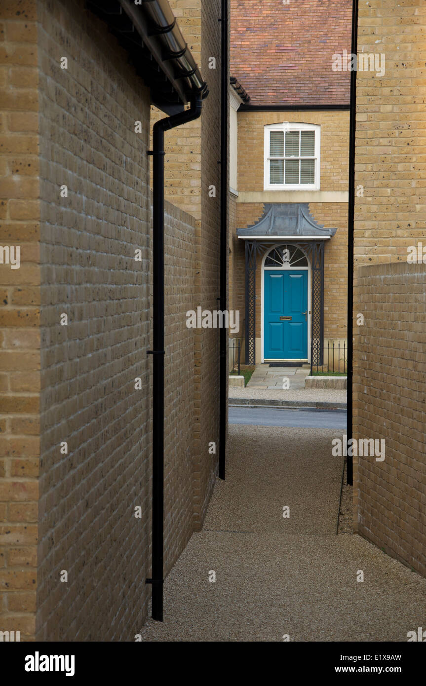 Architettura moderna. Uno stretto vicolo tra due case si apre su una strada e i telai della porta anteriore di una casa di fronte a. Poundbury, Dorchester, Regno Unito. Foto Stock